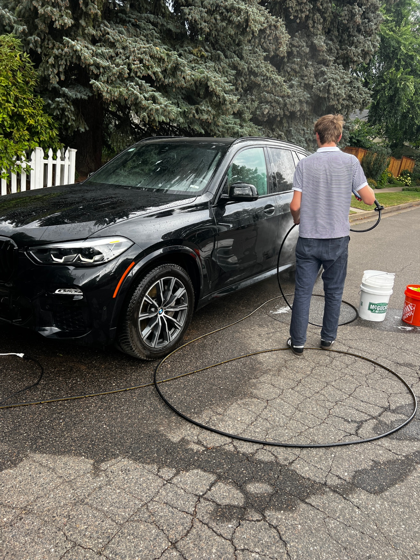 Hand-washing a black BMW X5 in a Boulder driveway